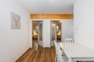 a white dining room with a white table and chairs at Schreinerfeld-Appartements in Ergolding +18 photos