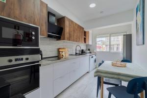 a kitchen with white cabinets and a table with blue chairs at Casa Solace in Almada