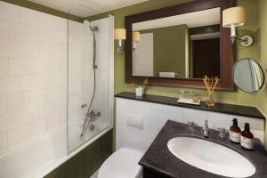 ein Badezimmer mit Waschbecken, Dusche und Spiegel in der Unterkunft NH Brugge in Brügge