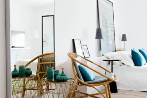 sypialnia z 2 krzesłami i łóżkiem z niebieskimi poduszkami w obiekcie CBbC Suites Port Vell w mieście Ibiza