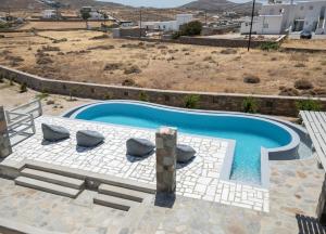 a swimming pool with two lounge chairs in front of a house at Ventus Studios in Ano Mera +22 photos