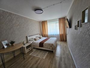 a bedroom with a bed and a table and a window at Апартаменти Aura Bliss in Zhytomyr