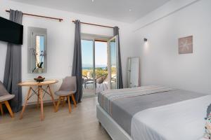 a bedroom with a bed and a table and a balcony at Sunshine Medousa Suite in Glifades