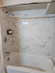 a white bath tub in a bathroom with marble tiles at For-Rest Inn and Spa in Bathurst +10 photos