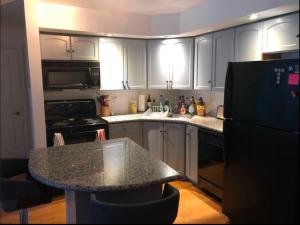 a kitchen with white cabinets and a black refrigerator at Downtown Toronto Condo in Toronto