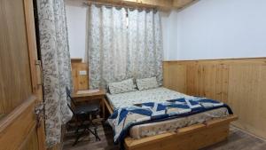a bedroom with a bed and a desk and curtains at Kunzang Homestay in Shalkār +15 photos