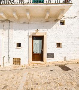 a white brick building with a door and a balcony at Casa del Ramaiolo in Alberobello