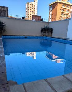 a blue tile swimming pool with buildings in the background at Hotel Armele Asunción in Asunción