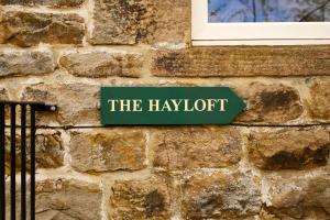 a sign on a brick wall that reads the laughter at Host & Stay - The Hayloft in Ilkley