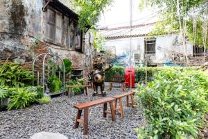 a garden with a statue and a bench and a building at Taladnoi 24 Hostel in Bangkok