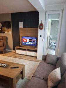 a living room with a couch and a tv at Nesi apartmenti in Prishtinë