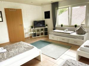 a living room with two beds and a television at Pension Platzhirsch Vogelsberg in Mücke +17 photos
