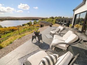 a patio with chairs and a view of a lake at Hanowen House in Dungloe