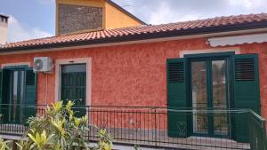 a red house with green shutters on a balcony at Domus amica 1 in Finocchito