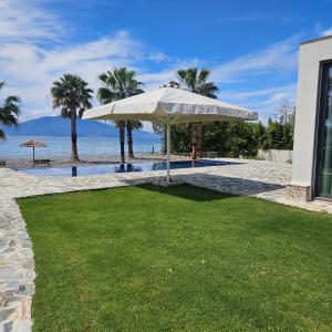 a white umbrella on a lawn next to a pool at Evia Palm Beach Villa in Politika
