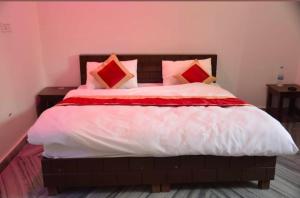 a large bed with red and white sheets and pillows at Hotel glass house in Kāta Patthar
