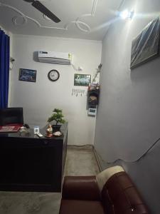 a living room with a couch and a clock on the wall at Hotel glass house in Kāta Patthar +2 photos