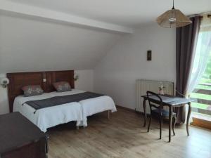 a bedroom with a bed and a table and a chair at "Parenthèse Alsacienne" in Luttenbach-près-Munster
