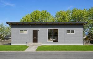 a small gray house with a window and grass at Aso Vista in Aso