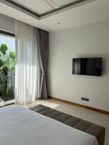 a bedroom with a bed and a flat screen tv at Lucky Eight Villa in Ban Phru Champa