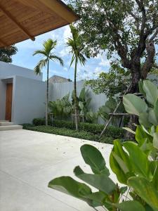 a courtyard with palm trees and a white fence at Lucky Eight Villa in Ban Phru Champa