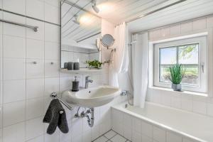 a white bathroom with a sink and a tub and a window at Achtern Diek in Schülp +37 photos