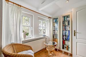a room with a chair and a table and bookshelves at Achtern Diek in Schülp