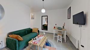 a living room with a green couch and a table at Appartement Elégant & Raffiné in Noisy-le-Grand