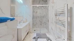 a white bathroom with a shower and a sink at Appartement Elégant & Raffiné in Noisy-le-Grand