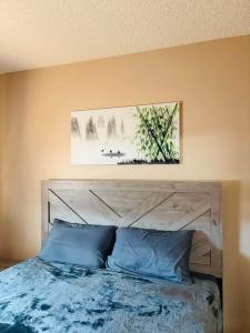 a bed with blue pillows and a painting above it at Belle-Rive - family friendly Guest House in Edmonton