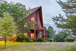 a log cabin house with a balcony on a lawn at Point Au Roche Lodge in Plattsburgh