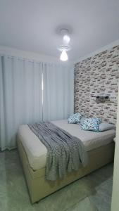 a bedroom with a large bed with a brick wall at Dois quartos mobiliado próximo a praia in Vila Velha