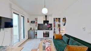 a living room with a green couch and a kitchen at Appartement Elégant & Raffiné in Noisy-le-Grand +6 photos
