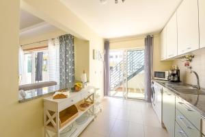 a kitchen with white cabinets and a large window at Olive Tree penthouse in Tavira