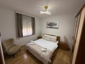 a bedroom with a bed and a chair and a window at Apartments Palić in Baška