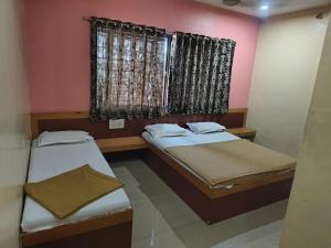 two beds in a room with a window at Hotel SS Palace in Shirdi