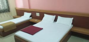 a small room with two beds with white sheets at Hotel SS Palace in Shirdi
