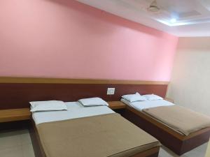 two beds in a room with a pink wall at Hotel SS Palace in Shirdi