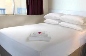 a white bed with a white towel and pillows on it at Americas Best Value Inn Irving DFW Airport South in Irving