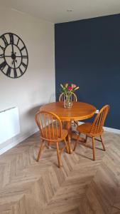 a wooden table with two chairs and a vase with flowers at Firthview Golspie in Golspie