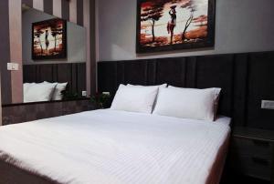 a bedroom with a large white bed with two pictures on the wall at Hotel House in Rishon LeẔiyyon