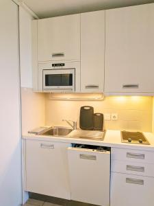 a white kitchen with a sink and a microwave at Alta Suarella in Saint-Florent