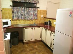 a kitchen with a white refrigerator and a sink at Aquarius Holiday Apartments in Batemans Bay