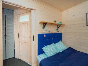 a bedroom with a blue bed and a wooden wall at Szum Fal in Rusinowo