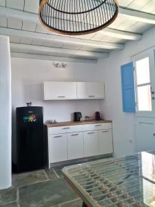 a kitchen with white cabinets and a black refrigerator at Flora's House in Livadakia +8 photos
