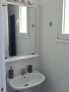 a white bathroom with a sink and a mirror at Flora's House in Livadakia