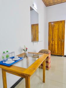 a wooden table with two plates and glasses on it at Nandana Homestay in Udawalawe