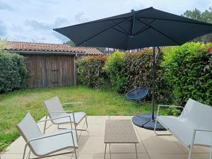 a group of chairs and an umbrella on a patio at Appartement proche lac et plage in Léon +3 photos