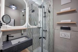 a bathroom with a shower with a sink and a mirror at Hotel Schäfflerwirt in Aschheim +44 photos
