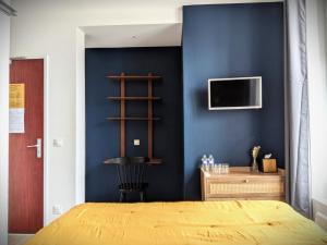 a bedroom with a blue wall with a bed and a tv at Hôtel Maisons Delphine - Le Cottage in Villers-sur-Mer